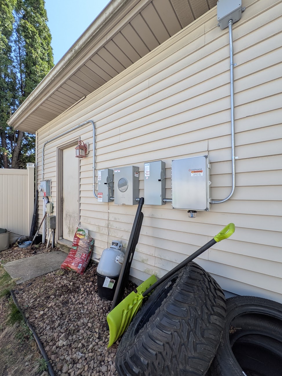 Exterior electrical enclosures and metal conduit mounted on a home with light-colored siding