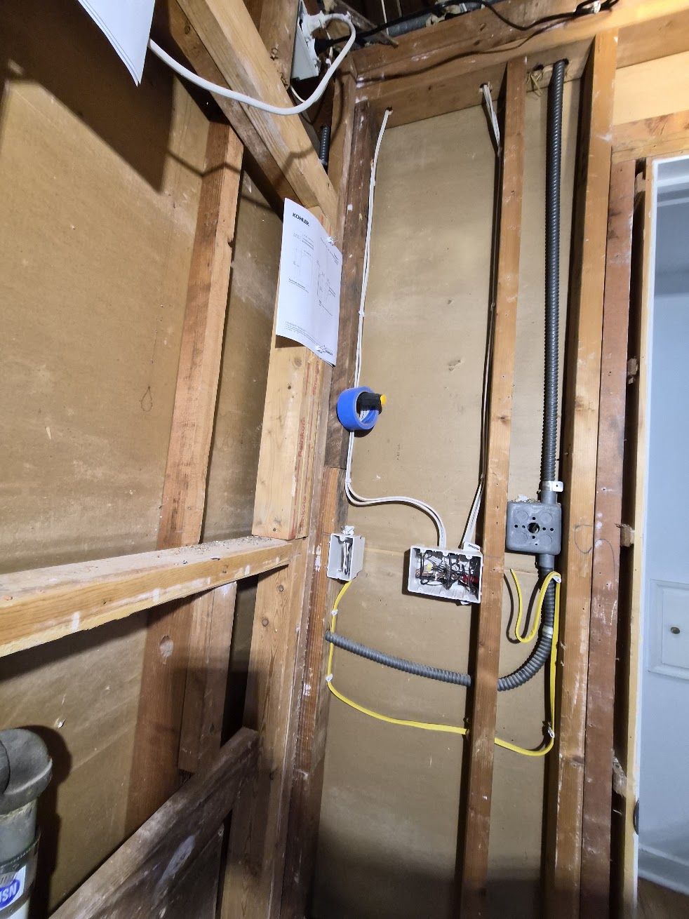 Open wall framing with a round fixture box, switch boxes, wiring and conduit