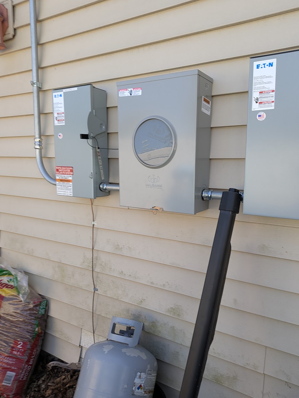 Close view of a meter enclosure and adjacent electrical disconnect enclosures connected by conduit